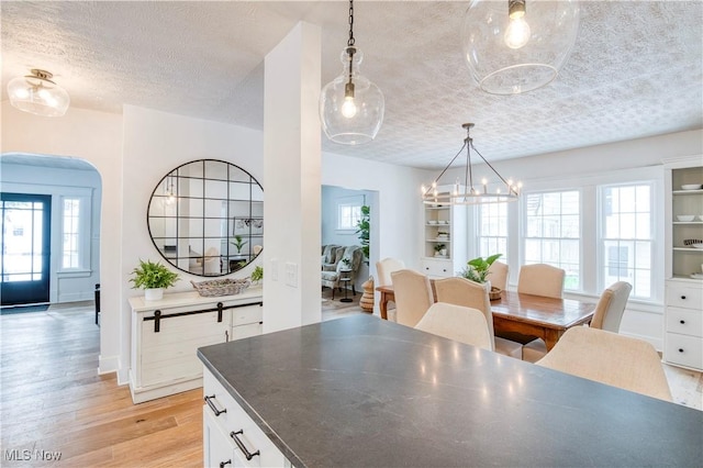 dining area with an inviting chandelier, light hardwood / wood-style floors, and a textured ceiling