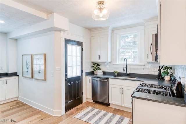 kitchen with stainless steel appliances, white cabinetry, sink, and light hardwood / wood-style floors