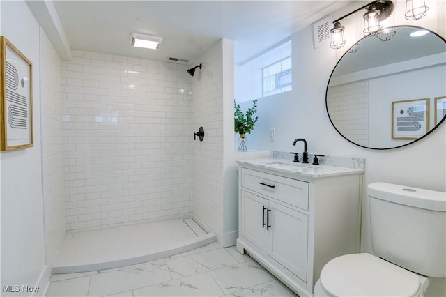 bathroom featuring vanity, toilet, and a tile shower