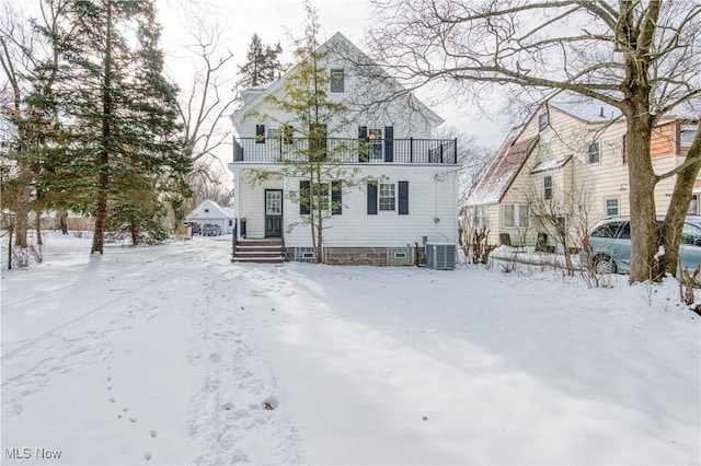 snow covered back of property with a balcony and central air condition unit