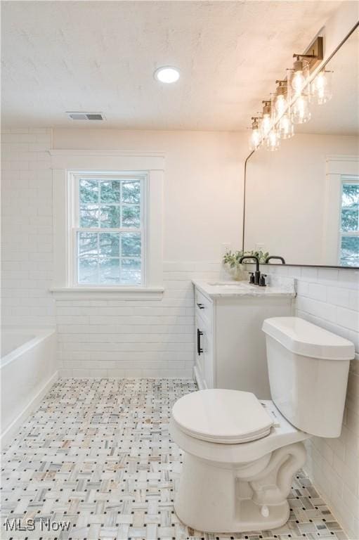 full bathroom with vanity, tile walls, tile patterned floors, and toilet