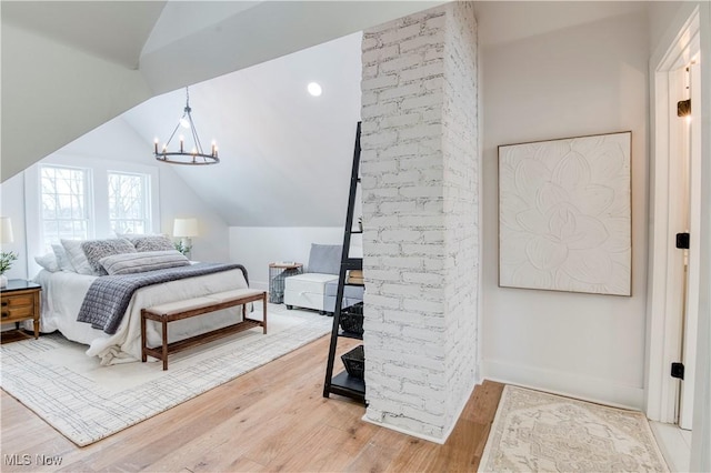 bedroom with lofted ceiling, hardwood / wood-style floors, and a chandelier