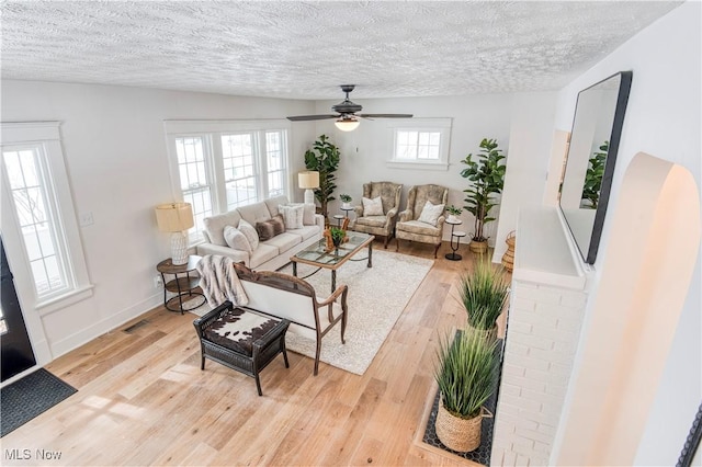 living room featuring ceiling fan, a textured ceiling, and light wood-type flooring