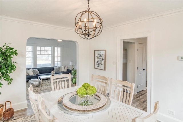 dining room featuring wood-type flooring, ornamental molding, and a notable chandelier