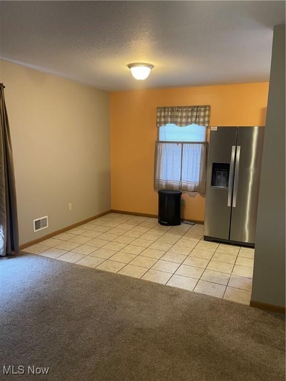 kitchen featuring light colored carpet, stainless steel fridge with ice dispenser, and a textured ceiling