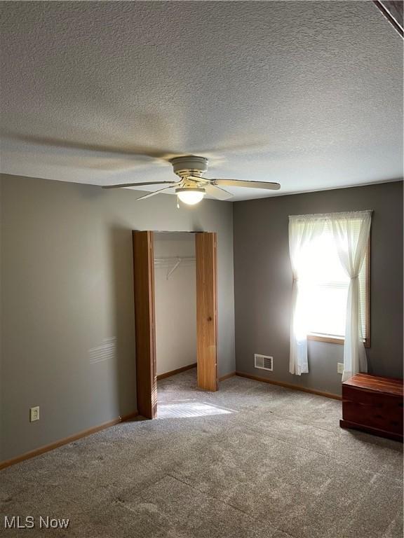 unfurnished bedroom featuring carpet floors, a textured ceiling, ceiling fan, and a closet