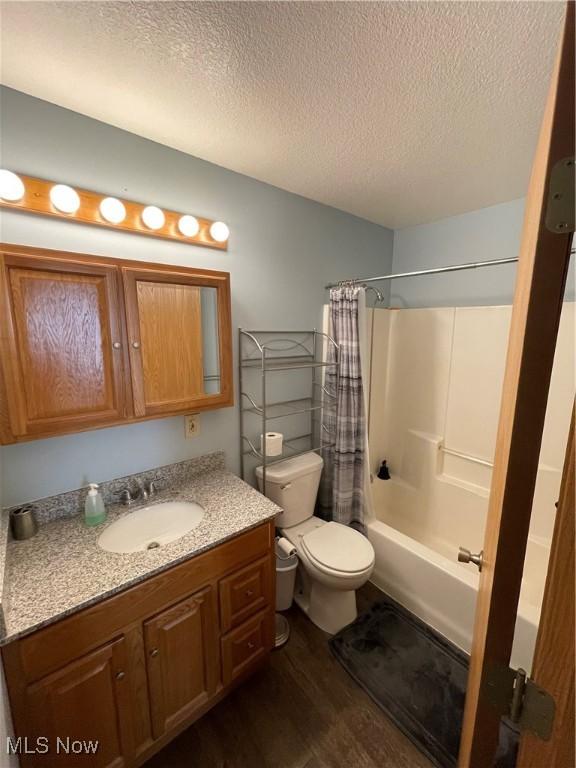 full bathroom with shower / bath combo, hardwood / wood-style floors, vanity, a textured ceiling, and toilet