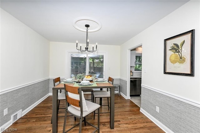 dining area with dark hardwood / wood-style flooring and an inviting chandelier