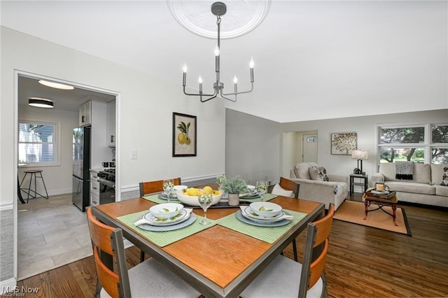 dining area with dark wood-type flooring and a notable chandelier