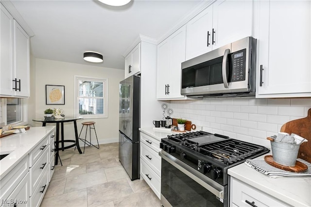 kitchen with light stone countertops, white cabinetry, appliances with stainless steel finishes, and backsplash