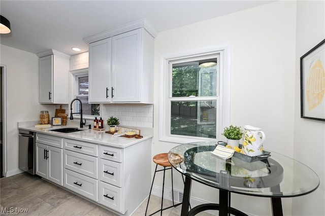 kitchen with dishwasher, sink, white cabinets, and decorative backsplash