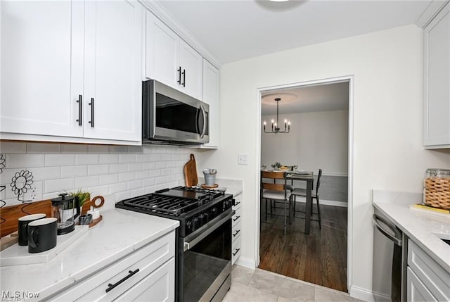 kitchen with stainless steel appliances, white cabinetry, light stone countertops, and decorative backsplash