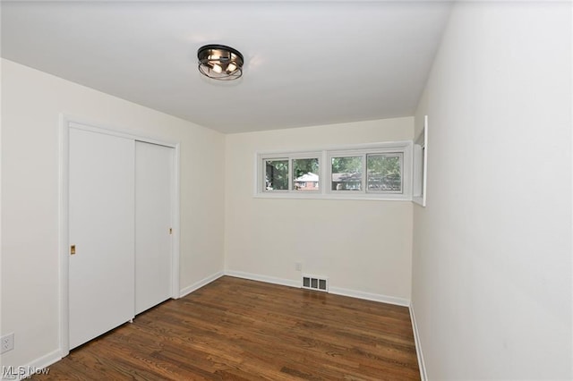 unfurnished bedroom featuring dark hardwood / wood-style flooring and a closet