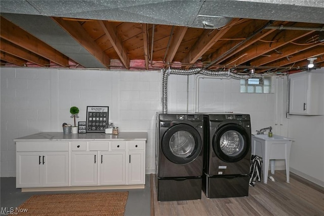 washroom with cabinets, wood-type flooring, sink, and washing machine and clothes dryer