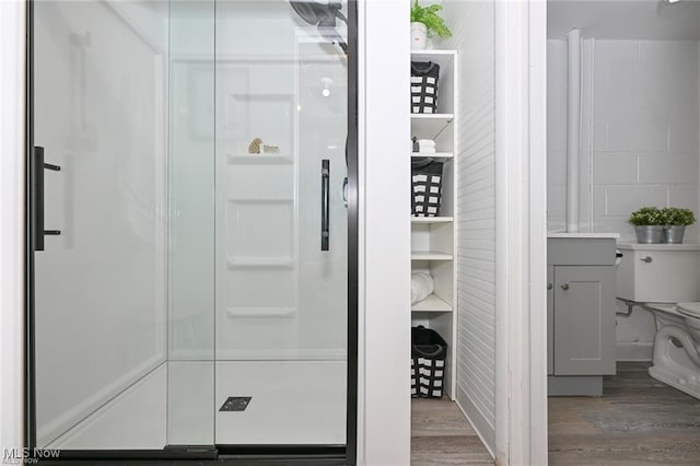 bathroom featuring toilet, a shower with shower door, and hardwood / wood-style floors