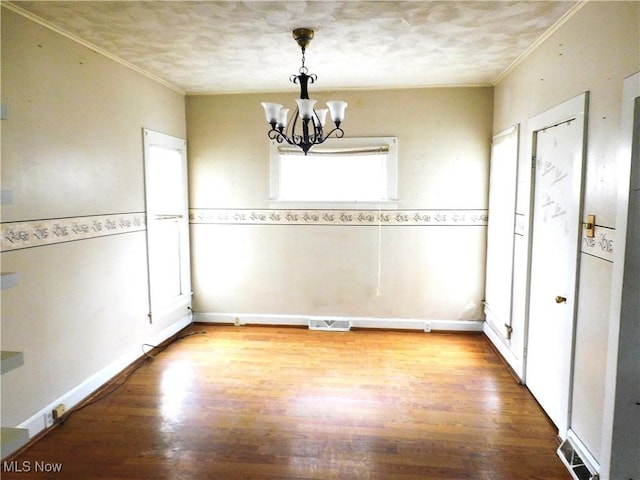 unfurnished dining area featuring an inviting chandelier, wood-type flooring, and ornamental molding