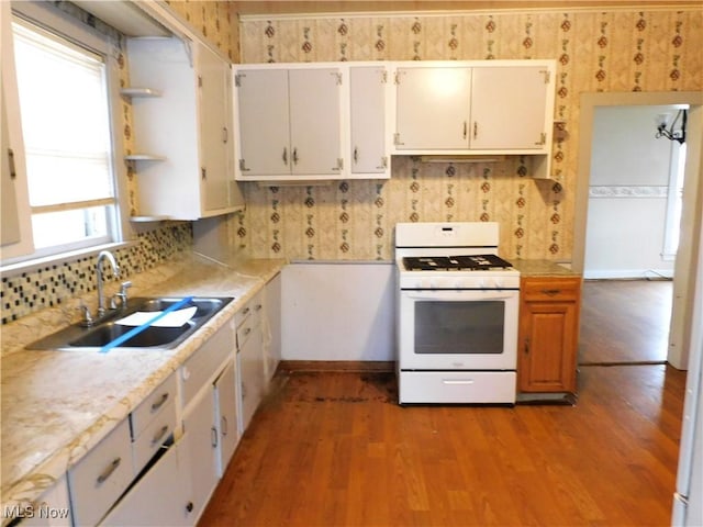 kitchen featuring tasteful backsplash, white cabinetry, wood-type flooring, sink, and white gas range oven