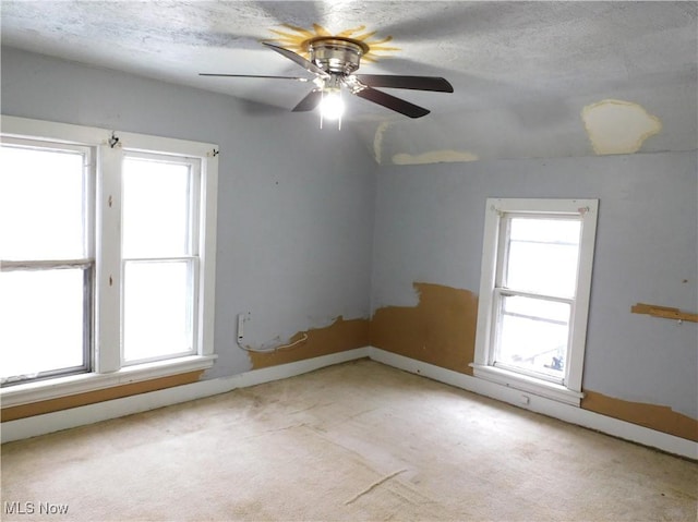 unfurnished room featuring ceiling fan, light colored carpet, and a textured ceiling