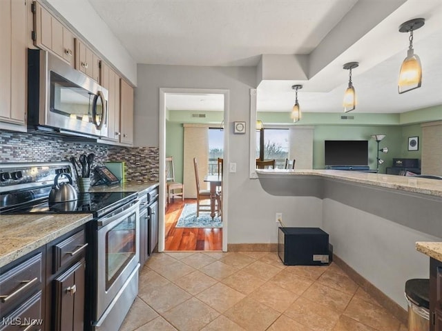 kitchen featuring pendant lighting, light tile patterned floors, appliances with stainless steel finishes, light stone countertops, and decorative backsplash