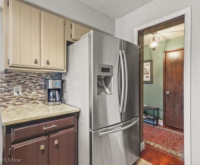 kitchen featuring hardwood / wood-style flooring, stainless steel fridge, tasteful backsplash, cream cabinets, and light stone counters