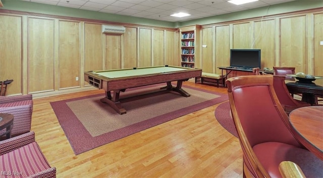 recreation room featuring billiards, a wall mounted AC, light hardwood / wood-style floors, a drop ceiling, and wood walls