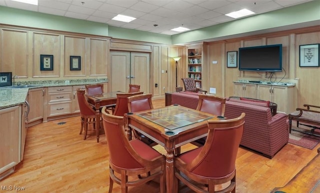 dining room featuring sink, a paneled ceiling, and light hardwood / wood-style flooring