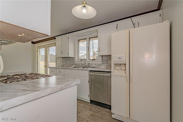 kitchen featuring white cabinetry, hanging light fixtures, stainless steel dishwasher, and white fridge with ice dispenser