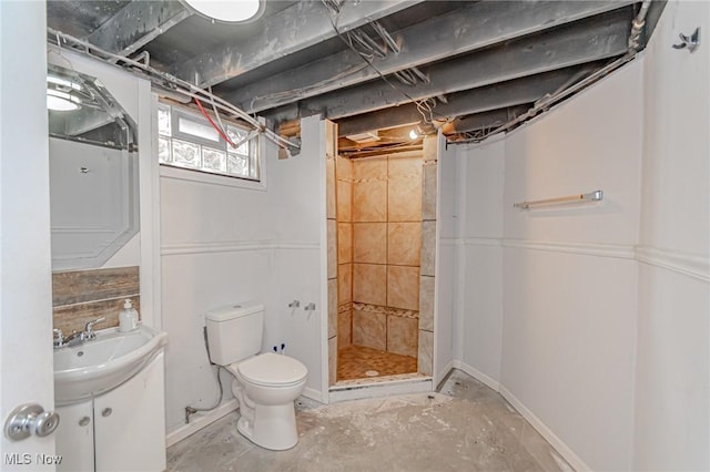 bathroom with tiled shower, vanity, toilet, and concrete flooring