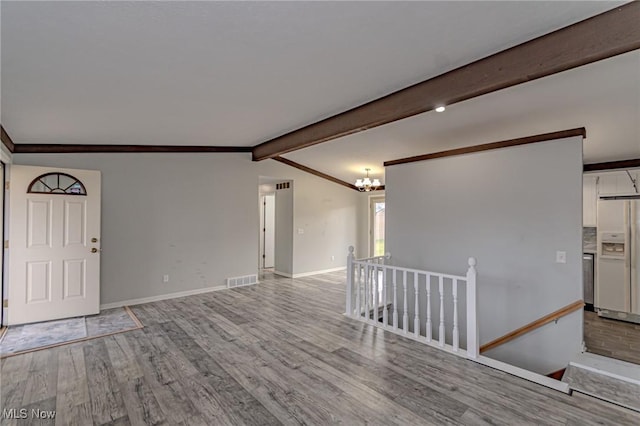 spare room featuring lofted ceiling with beams, crown molding, a chandelier, and light hardwood / wood-style floors