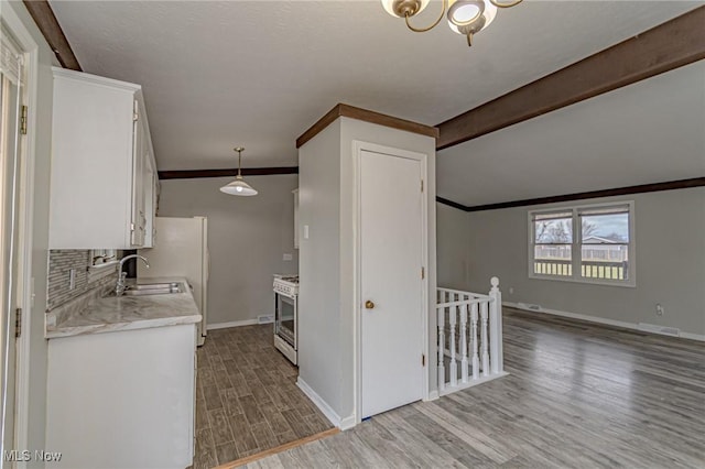 kitchen featuring sink, white cabinetry, hanging light fixtures, backsplash, and light wood-type flooring