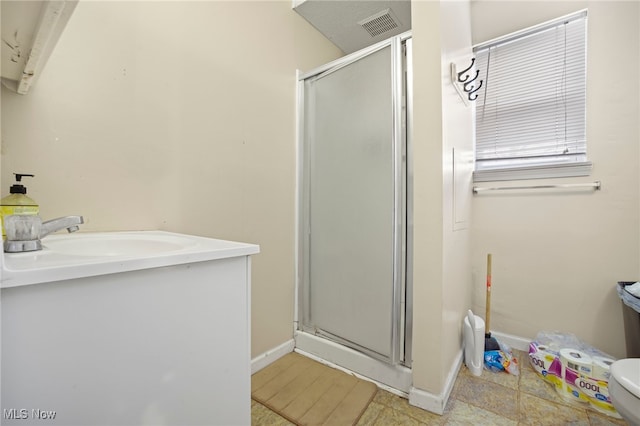 bathroom with sink, a shower with shower door, and toilet