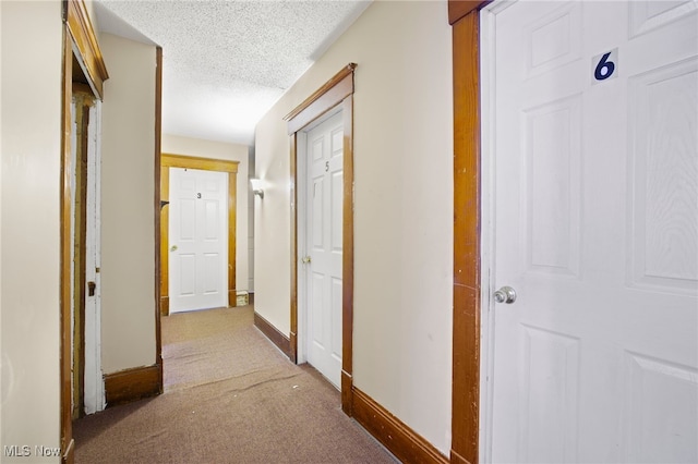 corridor with a textured ceiling and carpet