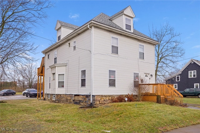 view of side of home featuring a deck and a lawn