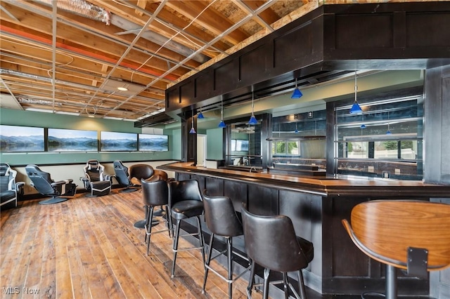 bar featuring hardwood / wood-style floors and hanging light fixtures