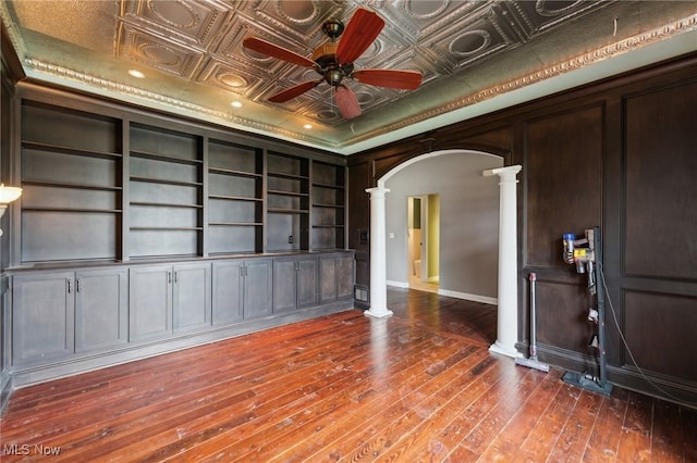 unfurnished living room with ornate columns, dark hardwood / wood-style floors, built in features, and ceiling fan