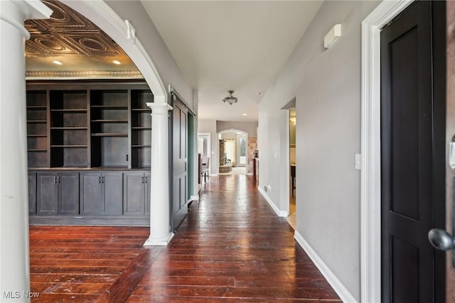 hall with dark wood-type flooring and decorative columns