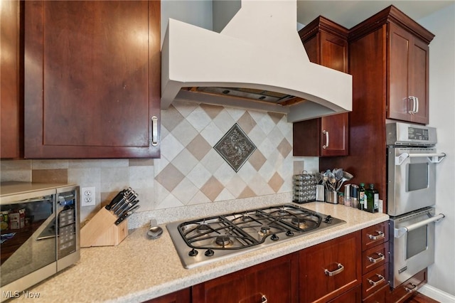 kitchen with decorative backsplash, stainless steel appliances, and premium range hood