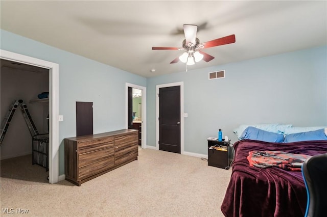 carpeted bedroom featuring ceiling fan and a walk in closet