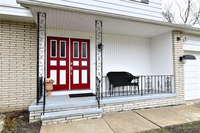 view of exterior entry featuring a garage and a porch