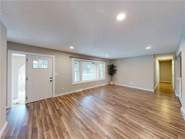 foyer entrance featuring a textured ceiling and light hardwood / wood-style floors