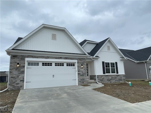 view of front of home with stone siding, an attached garage, and concrete driveway