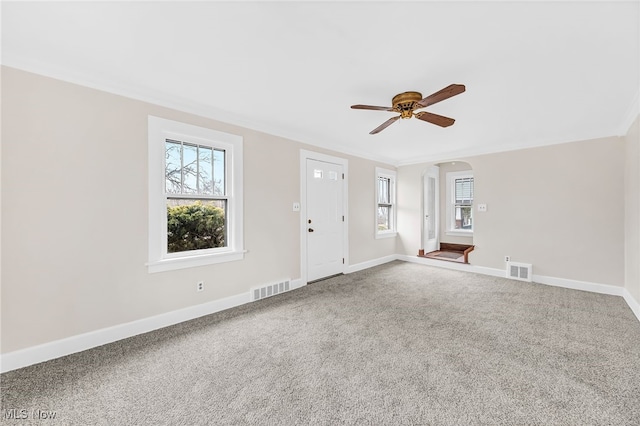 unfurnished living room with crown molding, ceiling fan, a healthy amount of sunlight, and carpet floors