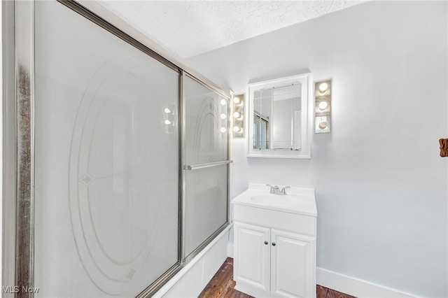 bathroom with enclosed tub / shower combo, wood-type flooring, vanity, and a textured ceiling