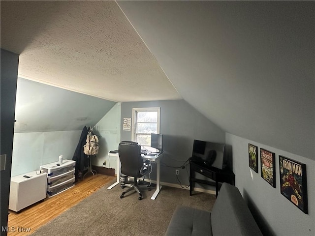 office space with wood-type flooring, vaulted ceiling, and a textured ceiling