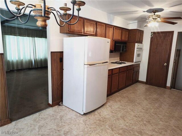 kitchen featuring ceiling fan with notable chandelier and white appliances