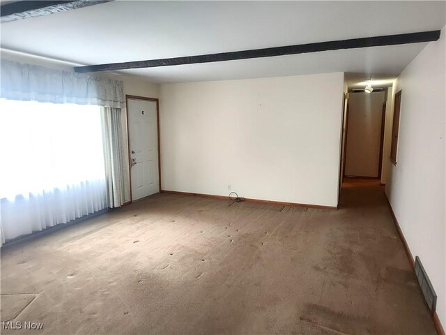 carpeted empty room featuring beamed ceiling