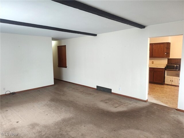 carpeted spare room with beam ceiling