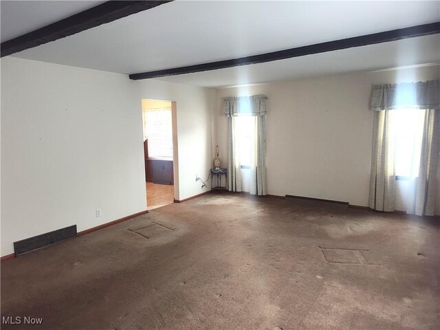 spare room with beam ceiling, carpet floors, and a healthy amount of sunlight