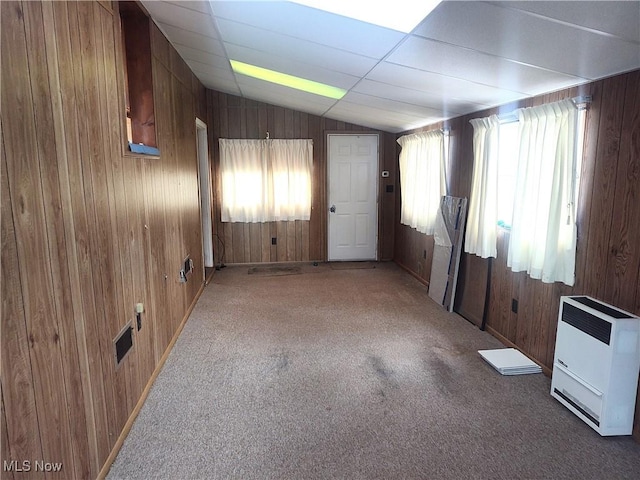 carpeted spare room with wooden walls and vaulted ceiling