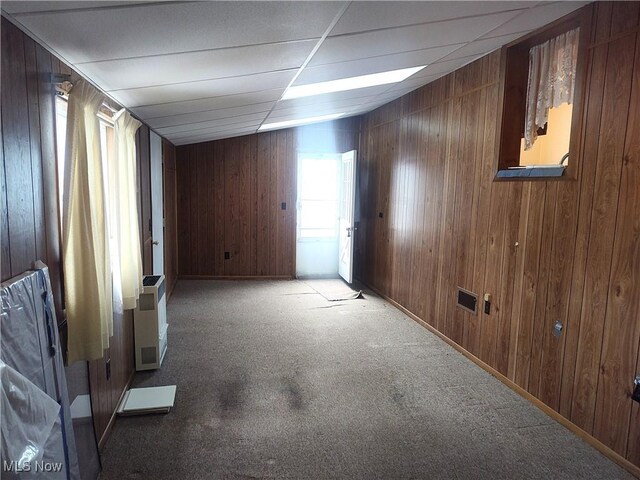 spare room featuring carpet floors, a paneled ceiling, and wood walls